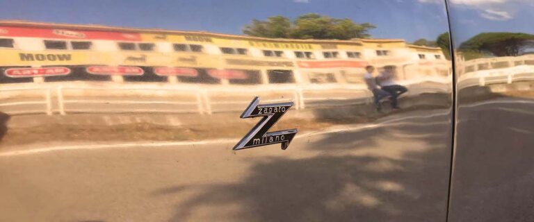 Zagato Milano badge on a classic Alfa Romeo reflecting the historic Cerda grandstand on Sicily's Targa Florio route.