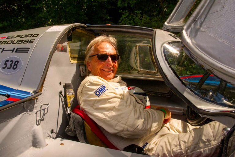 Historic racing driver seated in a prototype race car at the Goodwood Festival of Speed.