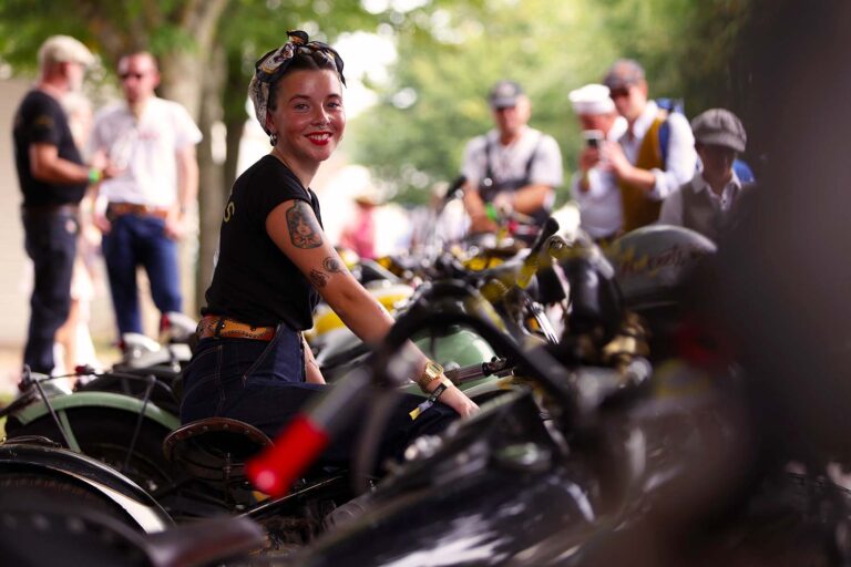 Besucherin zwischen historischen Motorrädern beim Goodwood Revival.