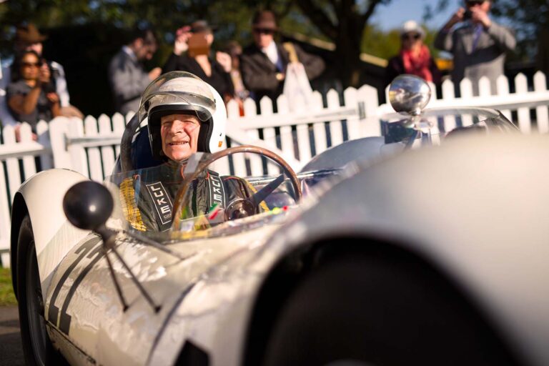 Historischer Rennfahrer im offenen Sportwagen beim Goodwood Revival.