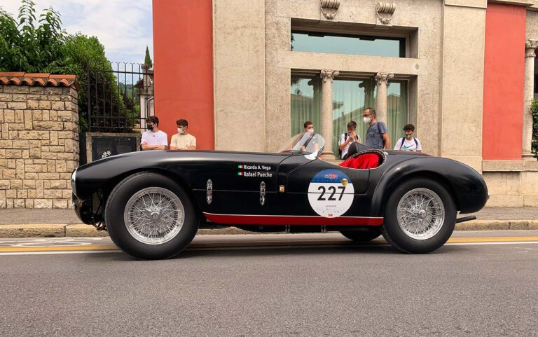 Black Ferrari Barchetta driving through an Italian town during the Mille Miglia.