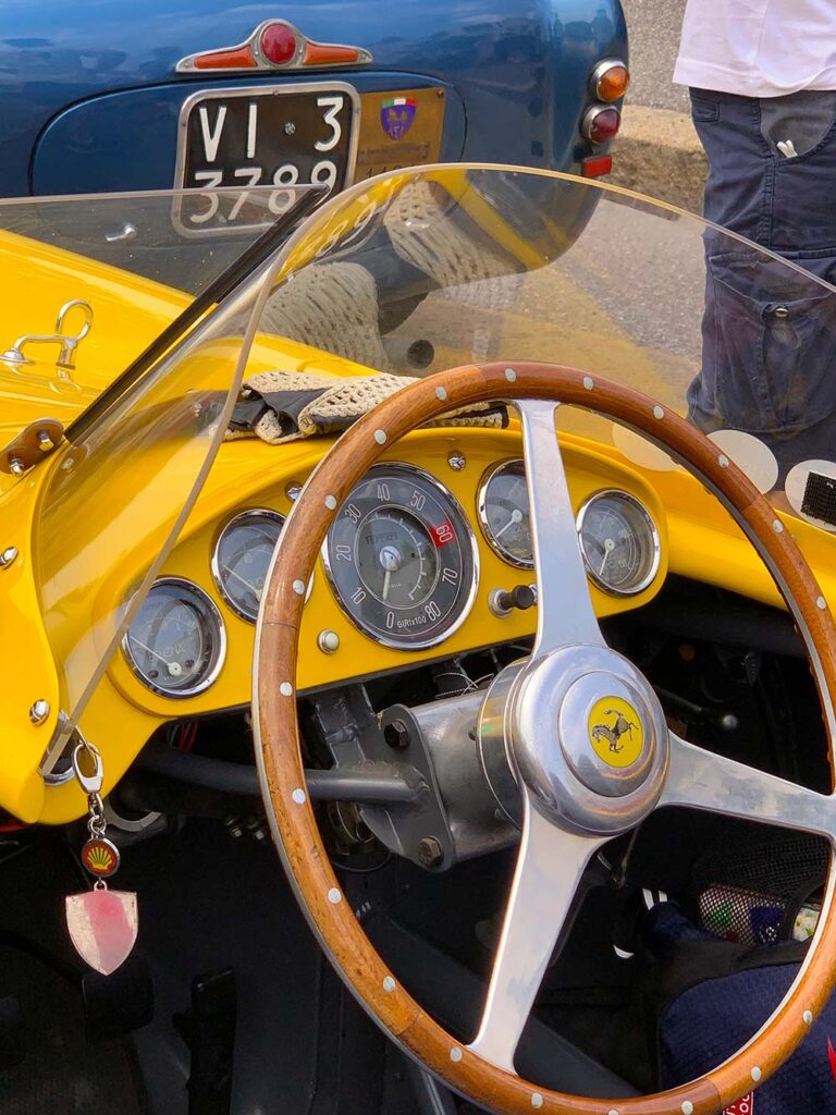 Close-up of a classic Ferrari cockpit with wooden steering wheel and vintage instruments during the Mille Miglia.