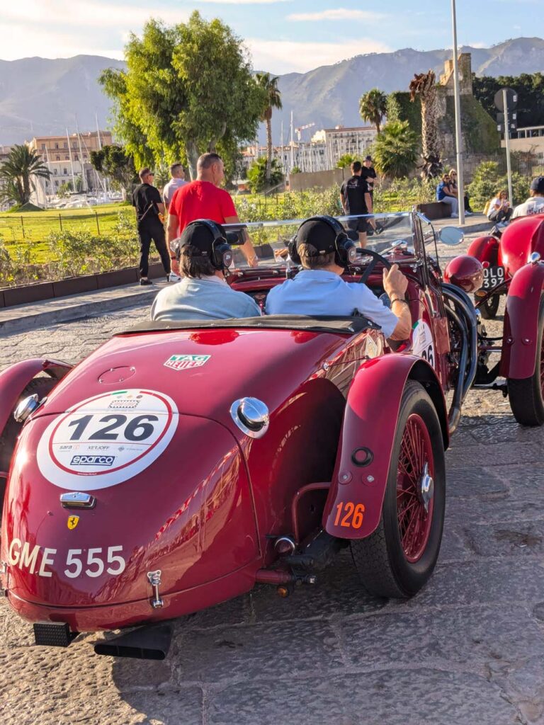Historic pre-war sports car with participants at Palermo's waterfront before the Targa Florio.
