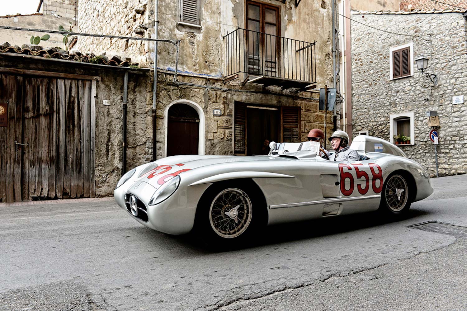 Mercedes-Benz 300 SLR driving through a historic Sicilian village on the legendary Targa Florio route.