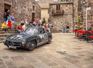 Mercedes-Benz 300 SL Coupé driving through a historic Italian village during the Mille Miglia.
